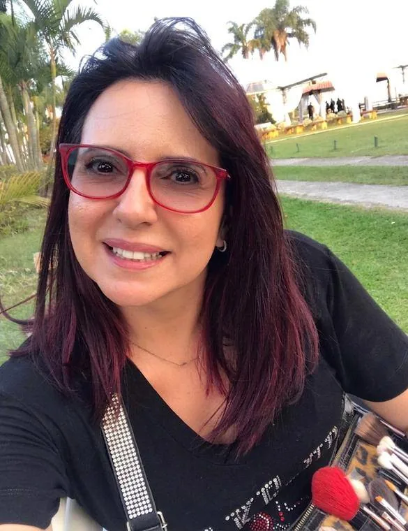 Guetti Reis sorrindo, com seu cinto de pincéis de maquiagem